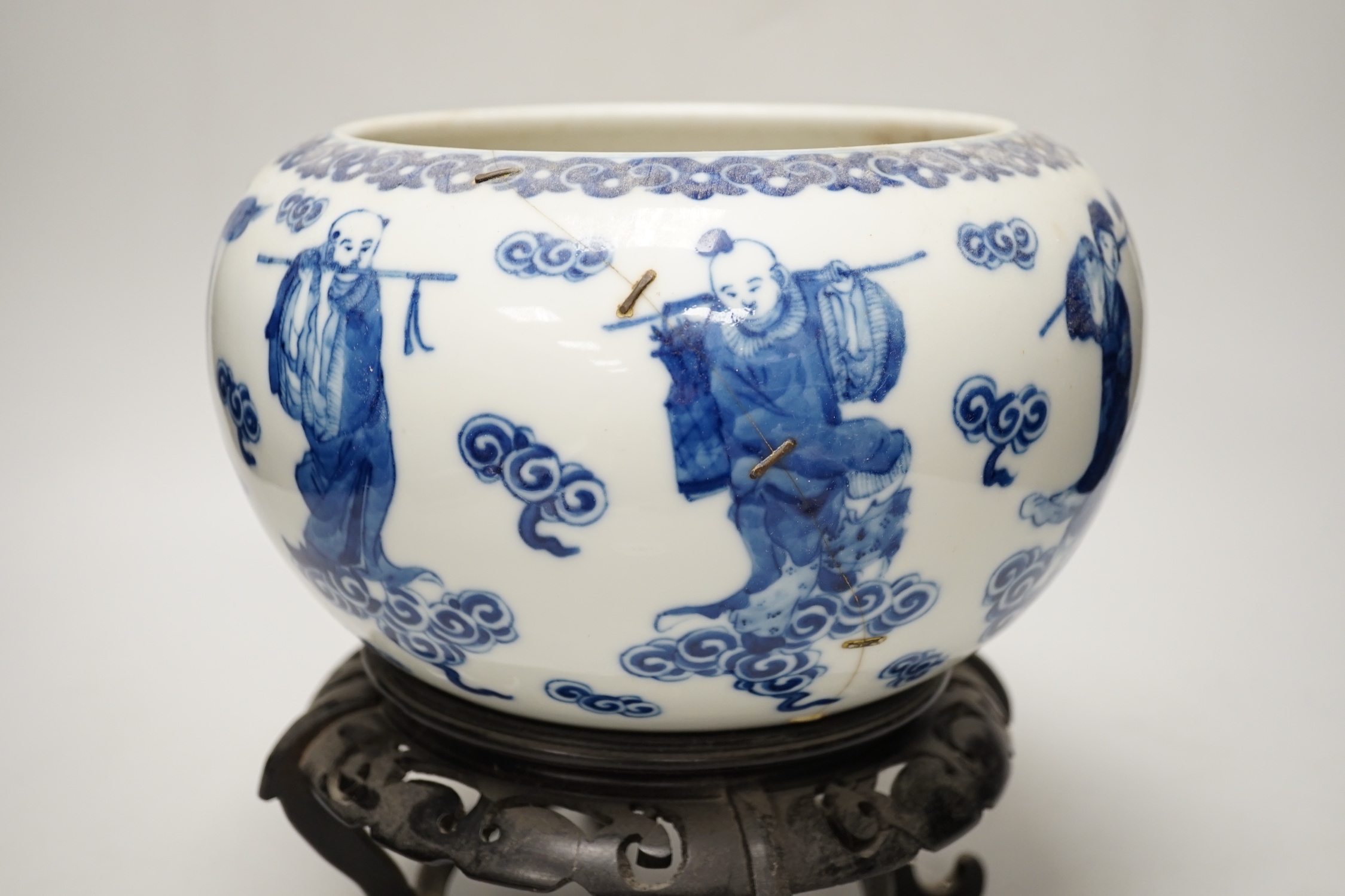 A 19th century Chinese blue and white ‘eight immortals’ alms bowl, apocryphal Qianlong seal mark, 25cm diameter (a.f.), wood stand